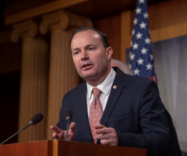 mike lee speaking in a suit and orange tie