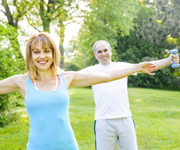 man and woman smiling, working out in park