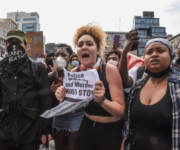 protesters dressed in black hold up signs and wear masks