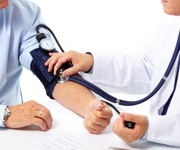 man getting his blood pressure checked by a physician with a blood pressure cuff