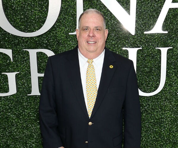 gov. larry hogan stands in front of a sign