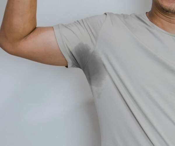 man holding arm up, showing sweat stain under arm