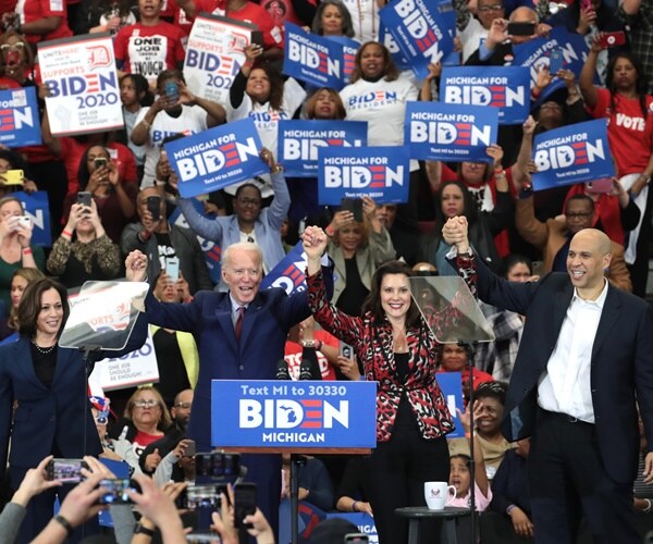 joe biden holds hands up in triumph with kamala harris, gretchen whitmer and cory booker