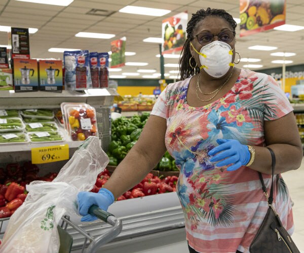 a woman is seen grocery shopping wearing a facial mask and blue gloves