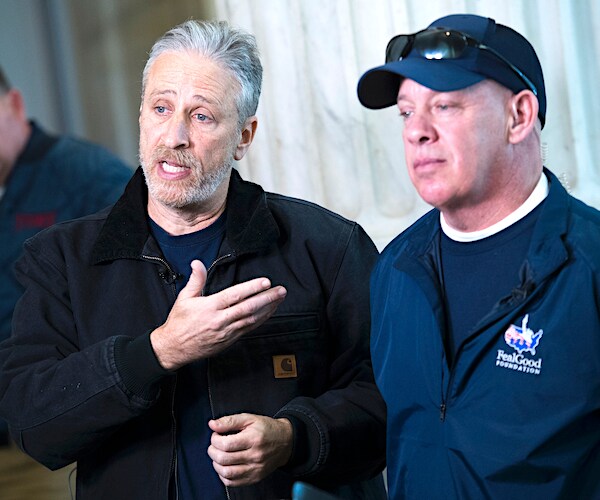 jon stewart gestures with his right hand pointing to nine-eleven first responder john feal while politicking on the hill