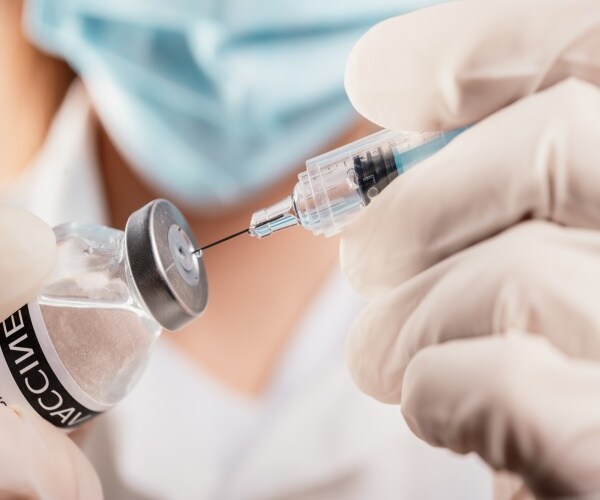 close-up of syringe in vial that says "vaccine"