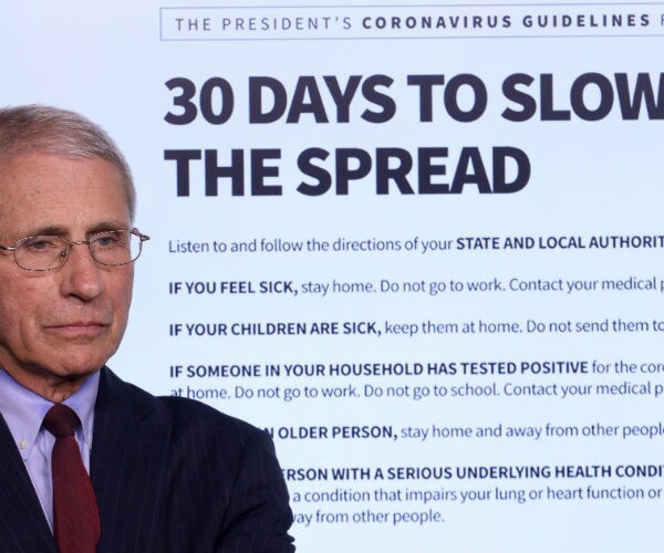 dr. fauci is shown standing beside a guideline list of what to do if you are feeling sick