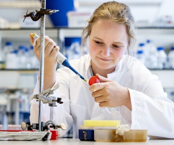 researcher in a white labcoat uses a pipette