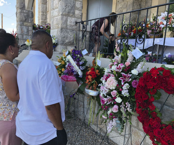 mourners standing outside church steps filled with flowers 