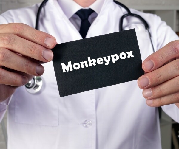 physician holding a sign that says 'monkeypox'