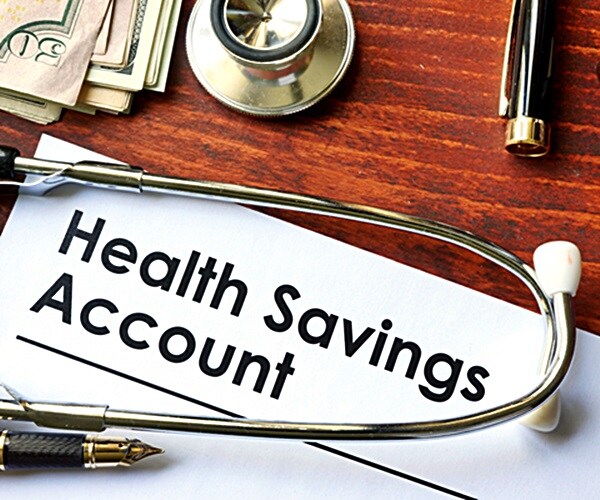 papers with health savings account hsa on a table with calculator and stethoscope