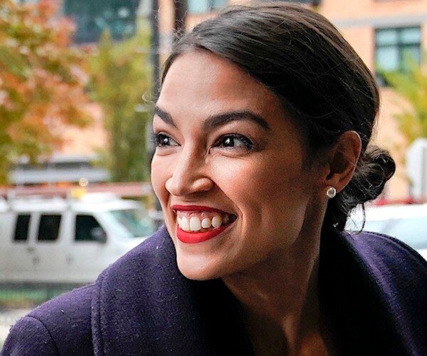 freshman lawmaker alexandria ocasio-cortez smiles as she looks back to her right