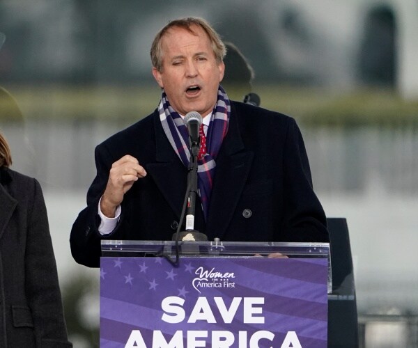 ken paxton stands at a lectern that says save america.