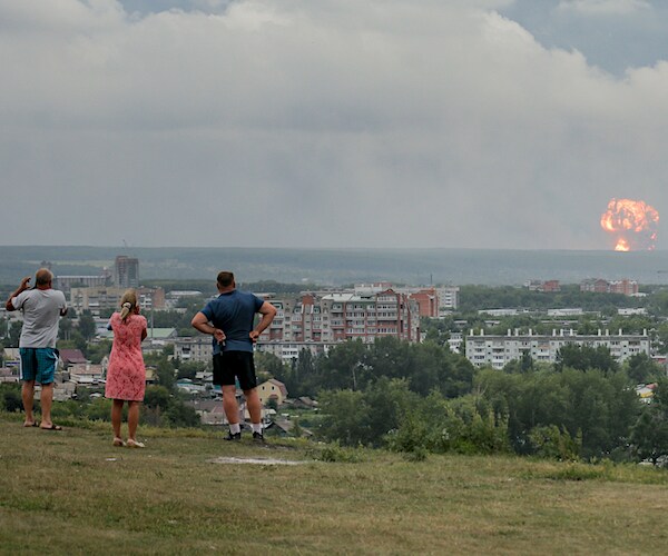 Russian onlookers watch a nuclear explosion mushroom cloud in the distance