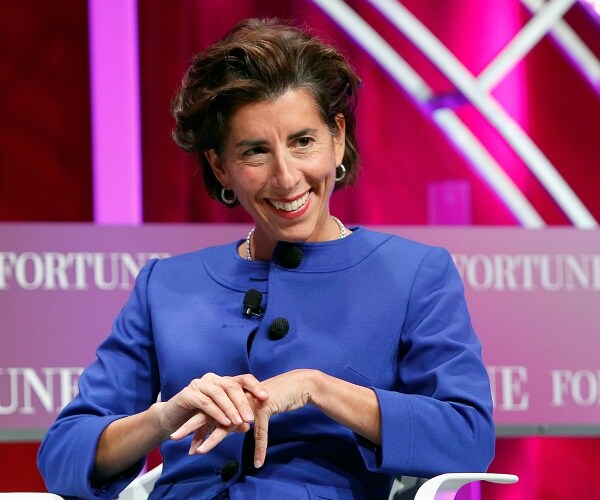 gina raimondo sits in chair onstage