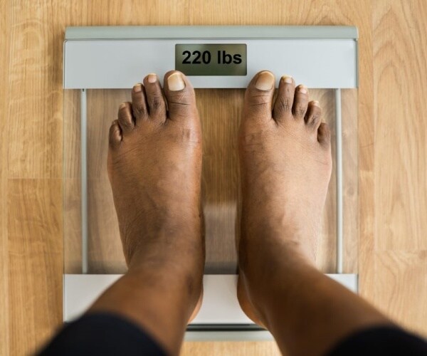 person standing on scale weighing 220 pounds