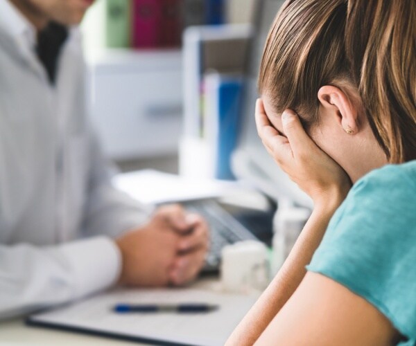 woman in despair talking to doctor in office