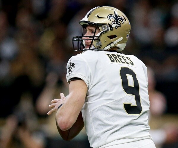 brees holding a football wearing a helmet and uniform