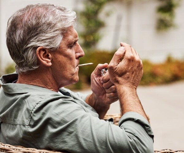 older man smoking a marijuana joint