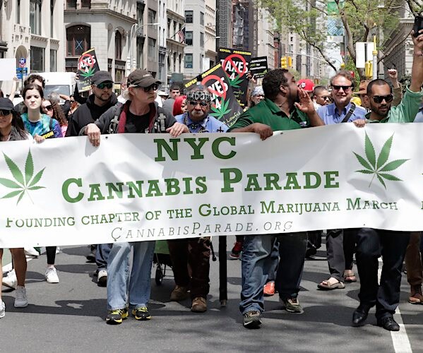 a cannabis parade marches thought new york city holding a sign reading nyc cannabis parade