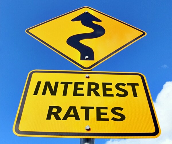 yellow and black Interest Rates Rising road sign with arrow in a blue sky 