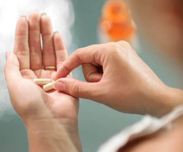 woman with two vitamin supplements in her hand