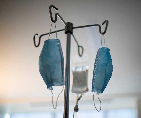 iv drip with masks hanging from iv pole in hospital