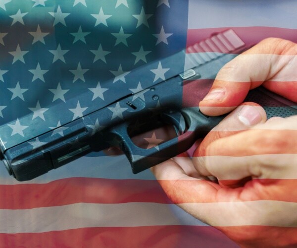 hand holding a gun, American flag behind