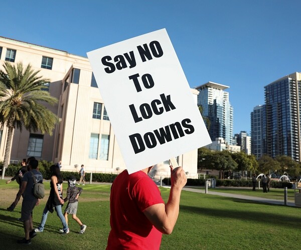 man holds sign that says say no to lockdowns