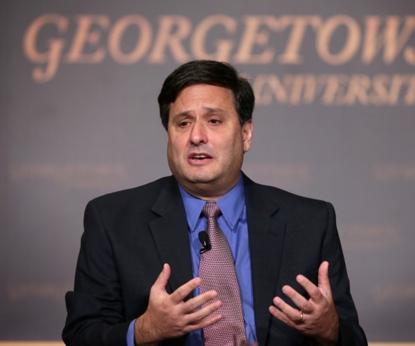 ronald klain in a blue shirt and black blazer speaking in front of a wall that says georgetown university