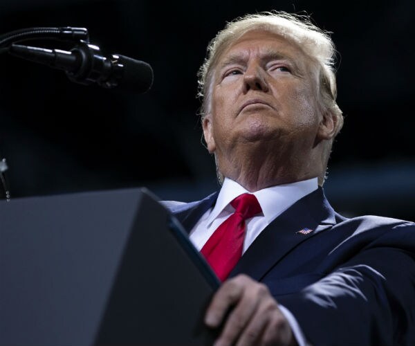 President Donald Trump in dark blue suit, dress shirt and red tie speaks during a campaign rally in Michigan.