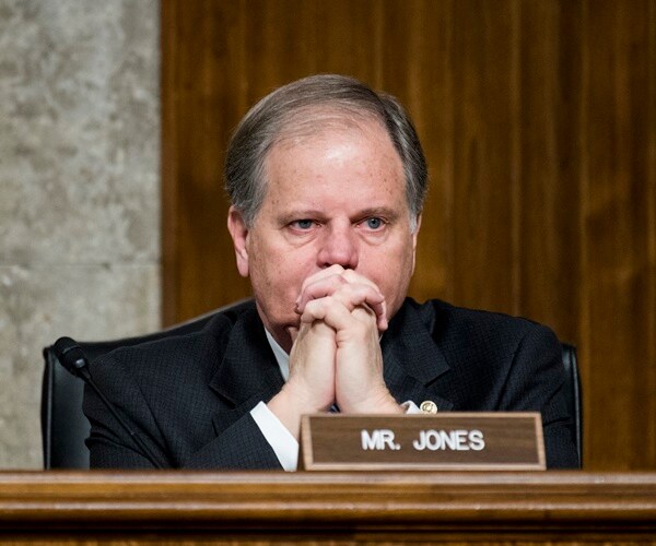 doug jones has his hands in front of him listening to testimony