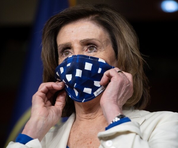 pelosi in a white blazer and blue and white face mask