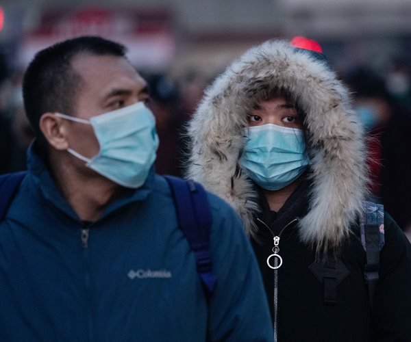 Chinese travelers wear protective masks in Beijing on Tuesday