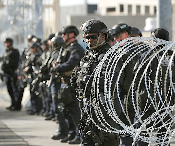 troops stand before barbed wire at the border