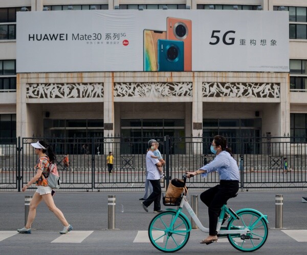 billboard advertising huawei 5g smartphones is seen as people walk and bike on the street in china