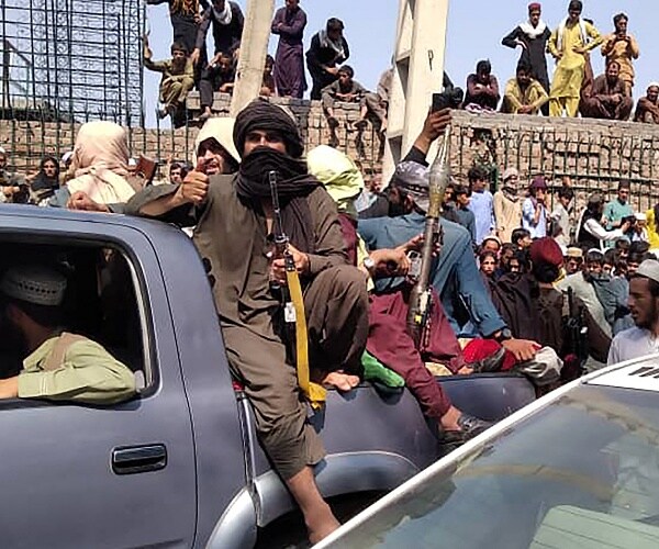 members of taliban sit in truck bed