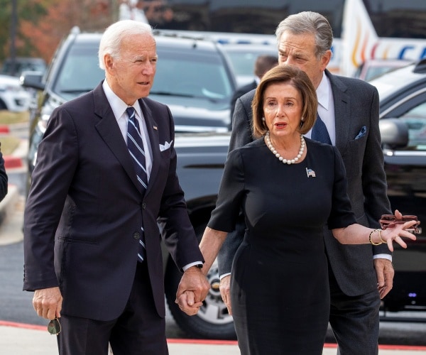 joe biden wearing a suit and striped tie holding nancy pelosi's hand