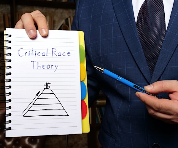 critical race theory on a placard in a photo illustration with a professor pointing at it with a pencil