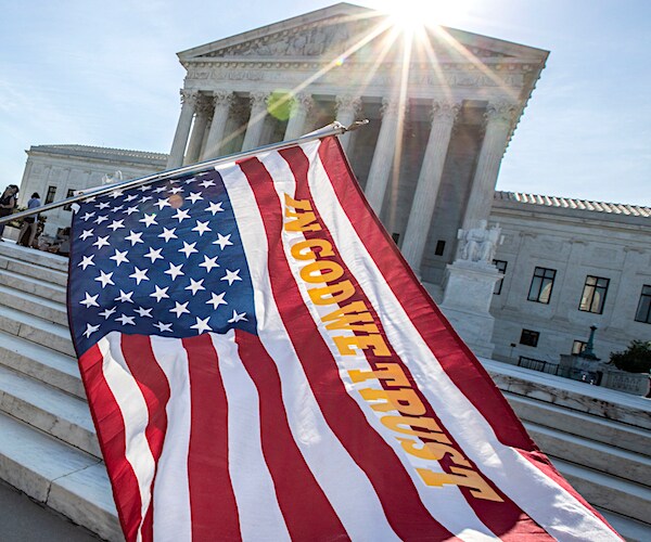 the steps of the supreme court building with an american flag reading in god we trust