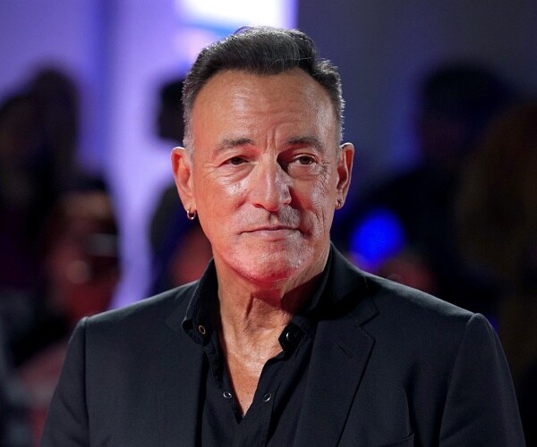 bruce soringsteen stands on red carpet