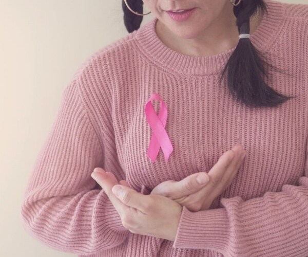 woman wearing pink sweater and pink breast cancer awareness ribbon