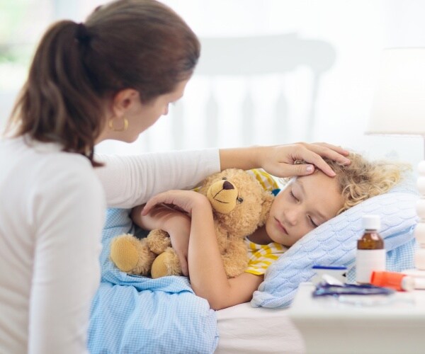 mother checking on sick child in bed