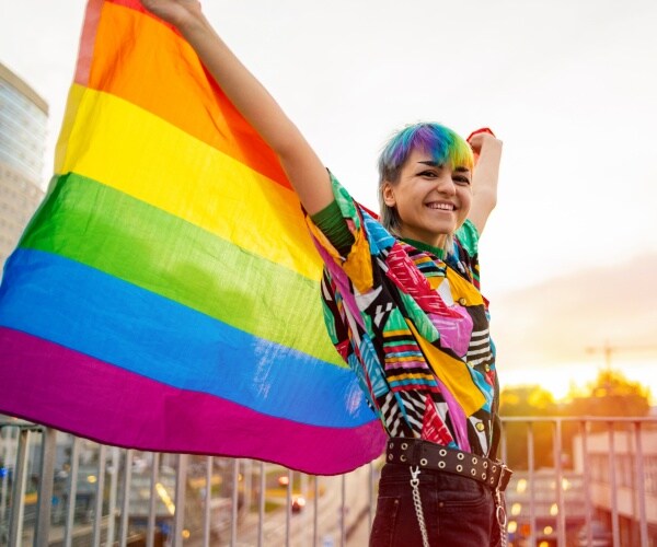 transgender youth holding rainbow flag