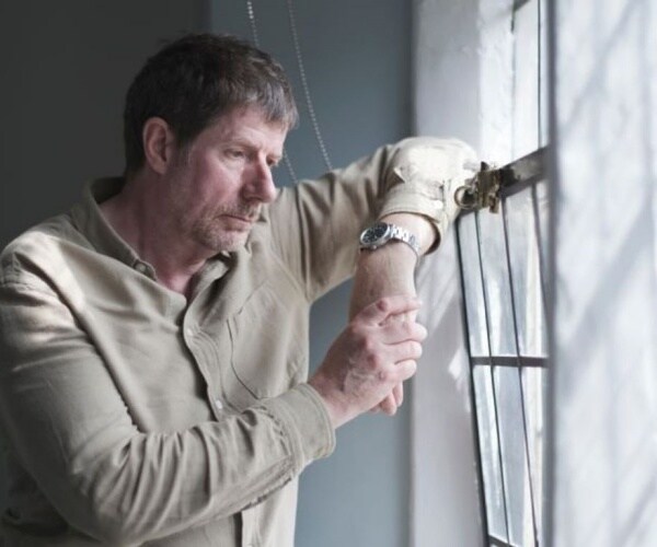 middle-aged man looking disheveled, looking out window