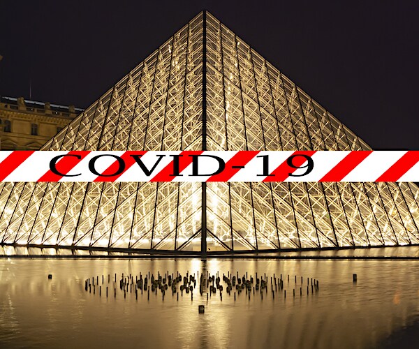 the louvre in paris, france is blocked by a railing marked covid-19