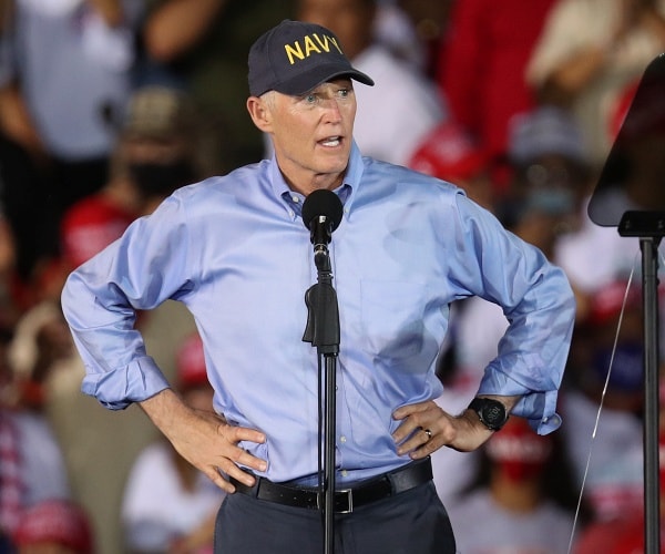 rick scott stands onstage with hands on hips