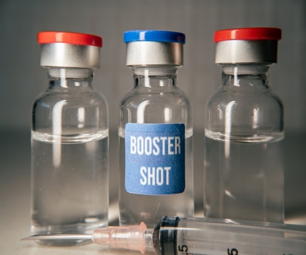 3 vials of COVID vaccine, the middle one is labeled "booster shot"