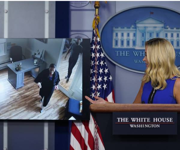 the white house press secretary looks at a video screen of pelosi at a hair salon