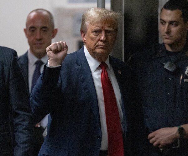 trump raises an encouraging fist toward the press as he passes outside the courtroom